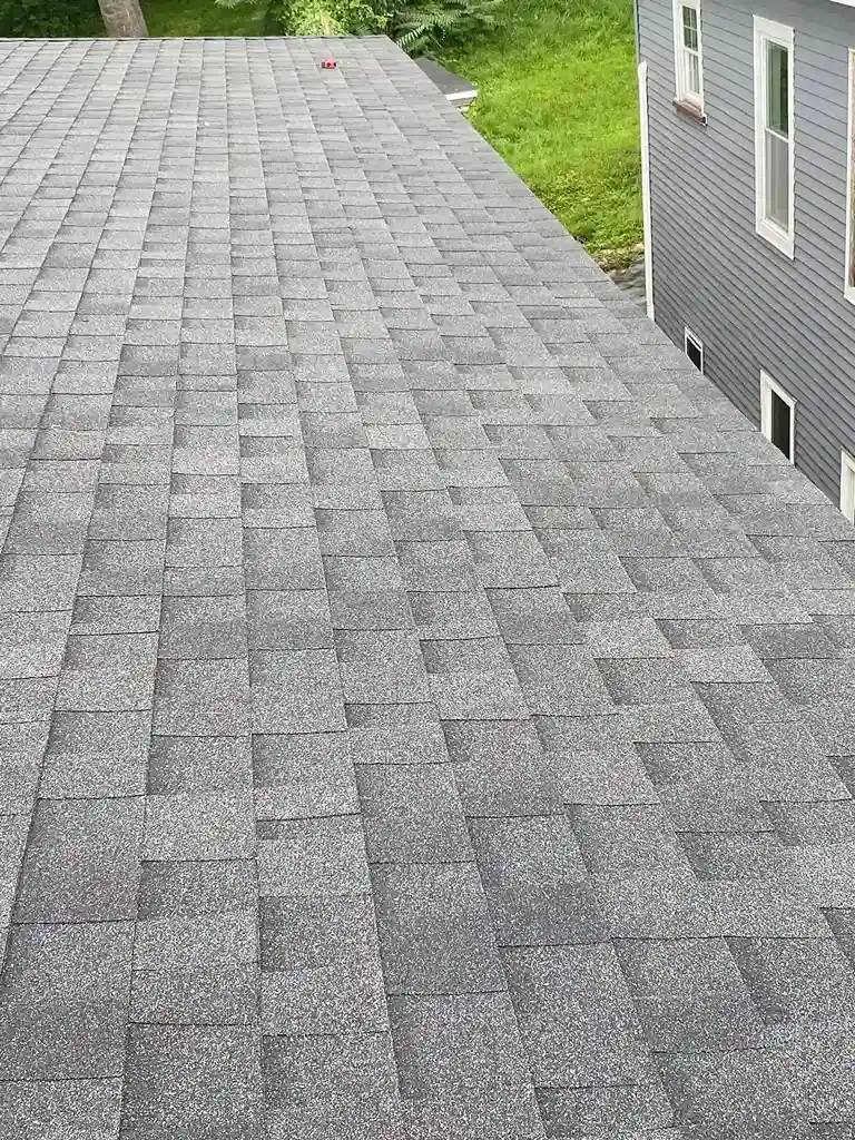 Clean, newly installed grey asphalt shingles neatly aligned on a residential roof.
